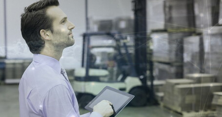 Warehouse manager using tablet to oversee inventory and logistics operations