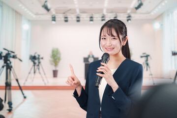 記者会見場からレポートをする女性のアナウンサー