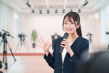 記者会見場からレポートをする女性のアナウンサー