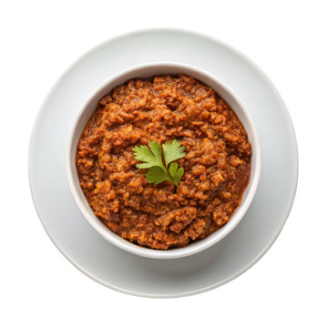 Savory kitfo dish served in white bowl, garnished with fresh herb, showcasing rich texture and deep flavors
