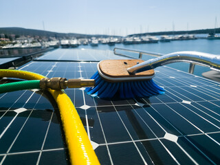 Close-up Sustainable Yacht and Solar Panel Maintenance with Water and Brush at a Bright Coastal...