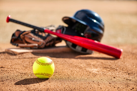 Close-up of optic yellow softball on red dirt infield with pitcher's mound pitching circle