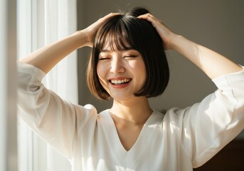 Fototapeta premium A joyful Asian woman with a short bob haircut and natural fringe smiling brightly with her eyes closed
