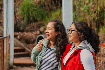 Fototapeta premium Two young latin american women admiring the view on a bridge