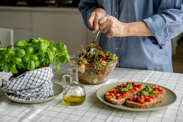 Women cooking salad with tomato tomato mozzarella vegetables and arugula in a large bowl 