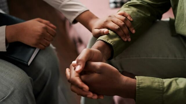 AI animated closeup of hand of anonymous African American female psychologist touching wrist of struggling male patient during therapy session in office, soothing while sharing painful memory or loss