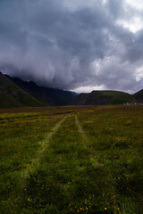 Off-road adventure through fields into the mountains. Majestic mountains tower in the background, lush greenery at your feet and ever-changing weather, storm clouds
