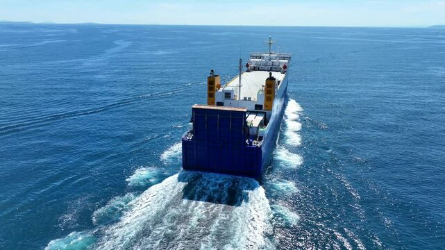 Aerial drone cinematic video of small car carrier ship RO-RO (Roll on Roll off) cruising in Mediterranean deep blue ocean sea