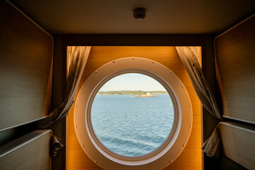 Scenic sea view through porthole from cozy cruise ship cabin interior window