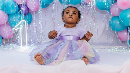 Fototapeta premium Beautiful baby, black girl, dressed as a princess celebrating her 1st birthday on a beautiful background. African girl, Black baby. Brazil, Rio de Janeiro