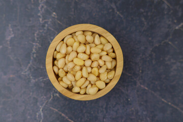 This image shows a topdown view of a bowl filled with delicious pine nuts, highlighting their color...
