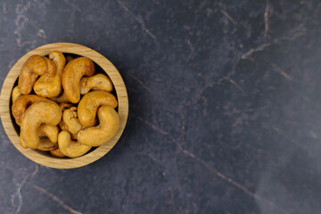 A beautifully arranged bowl filled with crunchy cashew nuts on a dark marble surface, perfect for a healthy snack
