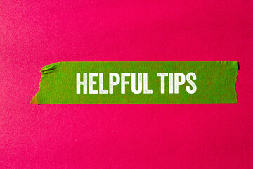 Helpful tips message written on ripped torn green paper tape on pink background. Conceptual helpful...