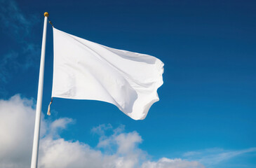 clear simple white flag waving against a clear blue sky.