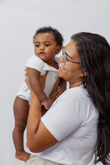 Beautiful Brazilian mother hugs and kisses her baby in the studio on a white background. A young...