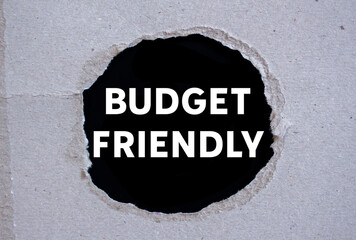 Budget friendly message written on ripped torn paper on black background. Conceptual budget...