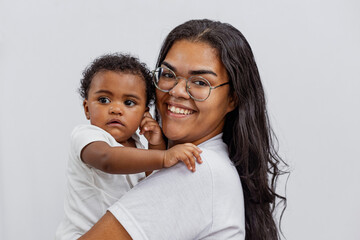 Beautiful Brazilian mother hugs and kisses her baby in the studio on a white background. A young...