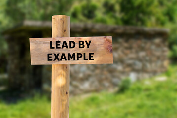 Lead by example message written on wooden sign on nature background. Conceptual lead by example symbol. Copy space.