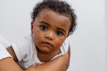 Beautiful Brazilian mother hugs and kisses her baby in the studio on a white background. A young...