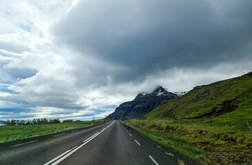 Naklejka premium Highway leading to snow capped mountain in Iceland under cloudy sky