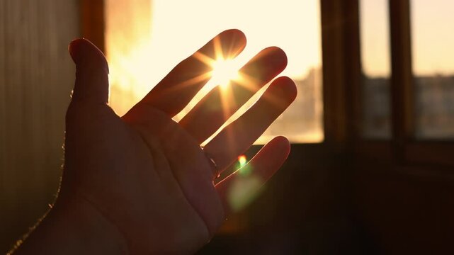 female hand playing with sunlight glare coming through window