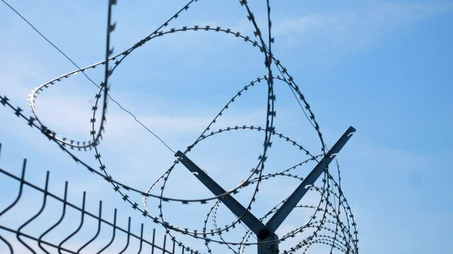 Metal fence with sharp barbed wire for protection, guard and defense of building, separation and control of restricted area, private industrial territory security concept.