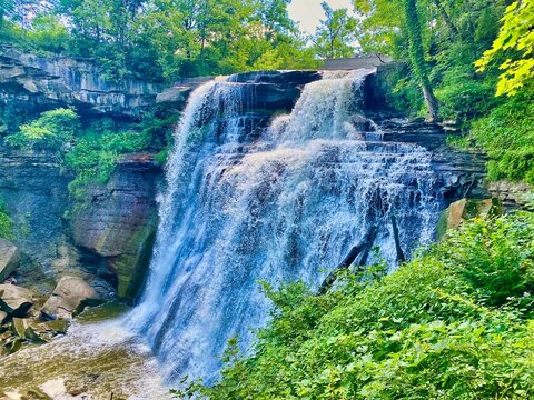 Waterfall cascading over a rocky cliff with lush greenery. - Powered by Adobe