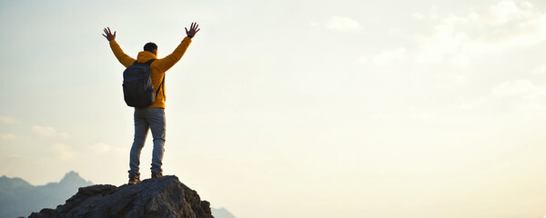 Man stands top mountain celebrating victory. Hiker raises arms in triumph, enjoying freedom, success. Person backpack on cliff against sunset backdrop. Inspiring image of achievement for travel,