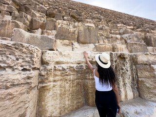 Feel the touch of Keops Pyramid as a tourist senses wonder in Giza, Egypt's ancient marvel. Experience one of the seven wonders of the modern world.