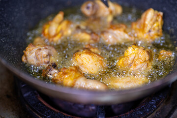 The oil is bubbling vigorously, indicating a high cooking temperature, and the chicken pieces are taking on a golden-brown hue.