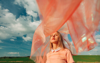 Woman in flowing pink fabric enjoying the outdoor breeze