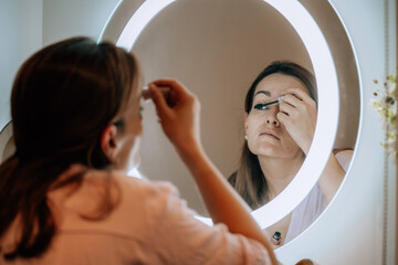 Mujer maquillandose frente a un espejo iluminado