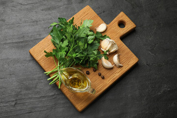 Fresh parsley and spices on black table, top view