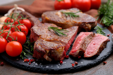 Pieces of delicious beef meat, spices and tomatoes on table, closeup