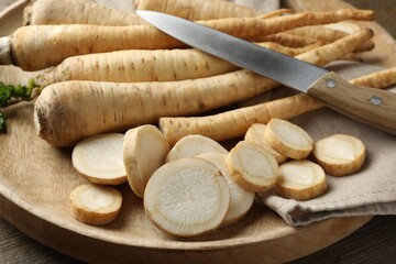 Parsley roots and knife on wooden table, closeup