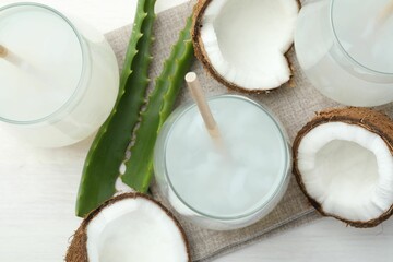 Refreshing drink with coconut and aloe on white table, flat lay