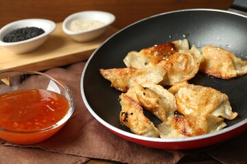 Tasty fried gyoza (dumplings) and sauce on wooden table, closeup
