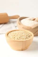 Brown rice and flour on white wooden table, closeup