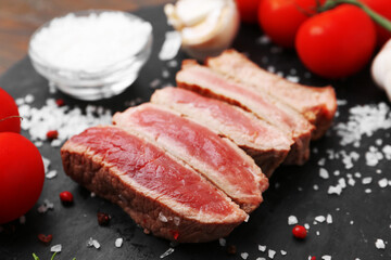 Fototapeta premium Delicious sliced beef tenderloin with different degrees of doneness, tomatoes and spices on table, closeup