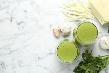 Healthy parsley smoothie, garlic, cabbage and leaves on white marble table, flat lay. Space for text