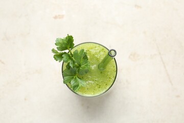 Healthy parsley smoothie in glass on light textured table, top view