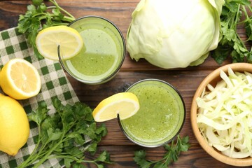 Healthy parsley drink in glasses, lemons and cabbage on wooden table, flat lay