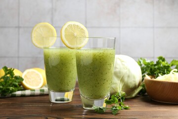 Healthy parsley drink in glasses, lemons and cabbage on wooden table, closeup