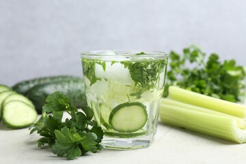 Healthy drink with parsley, cucumbers and celery on light table, closeup