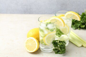 Healthy drink with parsley, lemons and celery on light grey table, space for text