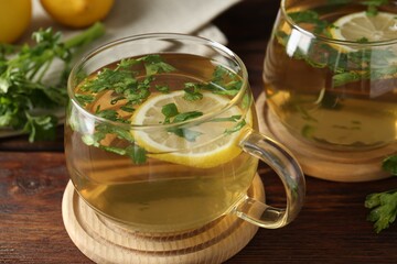 Healthy parsley tea with lemon slices on wooden table, closeup. Detox drink