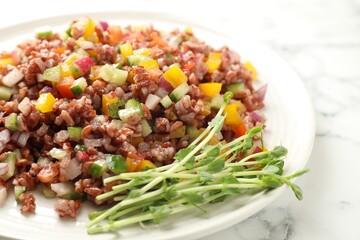 Tasty salad with brown rice on white marble table, closeup