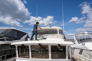 Boat maintenance worker providing cleaning service on a moored yacht. Maritime professional washing...
