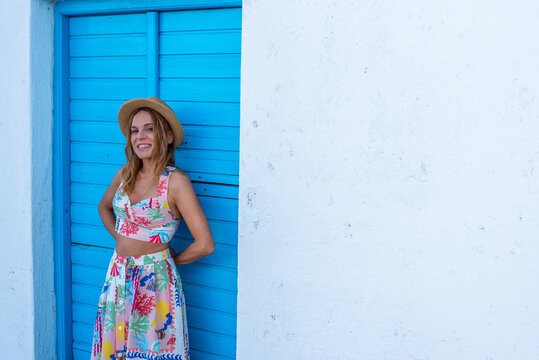 Woman in colorful summer attire by blue door in Triovasalos