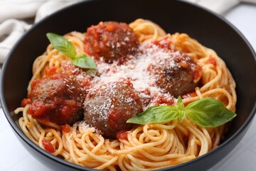 Delicious pasta with meatballs and cheese in bowl on white table, closeup